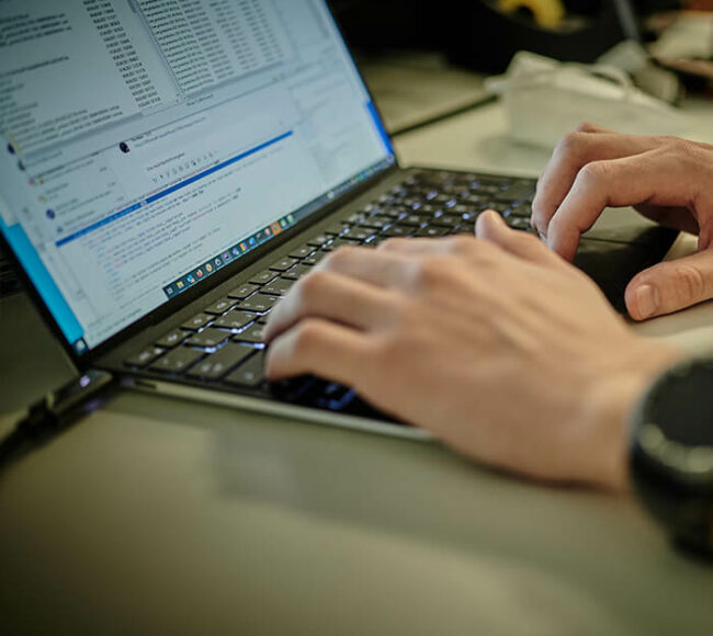 Mann tippt auf dem Laptop